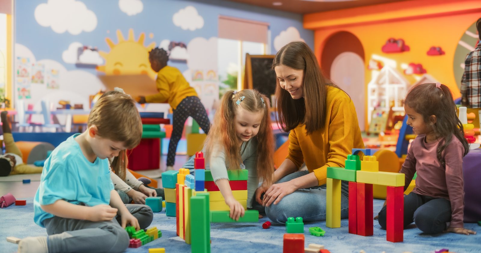 Teacher playing with children and building blocks